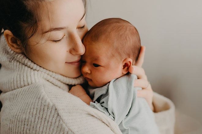 mother snuggling a newborn to her face